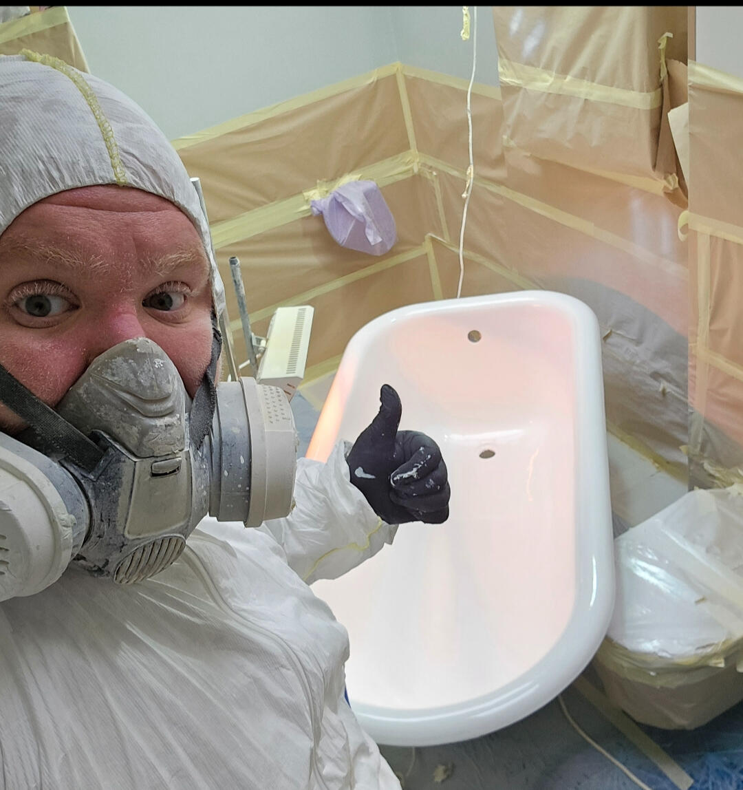 photo of glossy baths owner photo of glossy baths re-enamelling owner Seamus with a thumbs up, in ppe, in a room full of masking up and a completed bath in Bristol